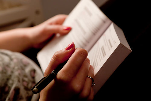 Close-up-of-a-teen-girl-making-notes-in-a-book